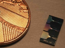 A photonic chip next to a UK penny