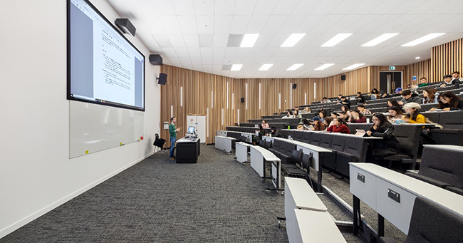 A large room with lecture style seating and large screen
