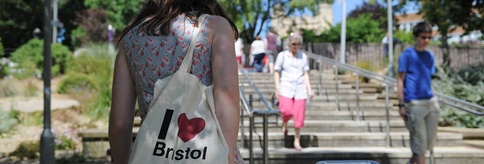 Woman walking up steps carrying a Bristol bag