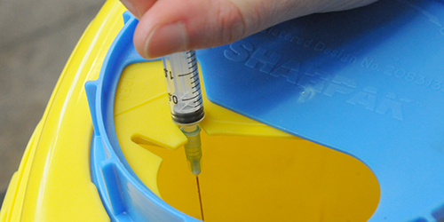 person placing needle in to sharps bin